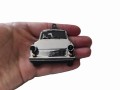 Brelok w kształcie białego modelu samochodu Trabant prezentowany na dłoni