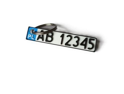 Biały brelok w kształcie tablicy rejestracyjnej z własnym napisem, ujęcie z przodu
